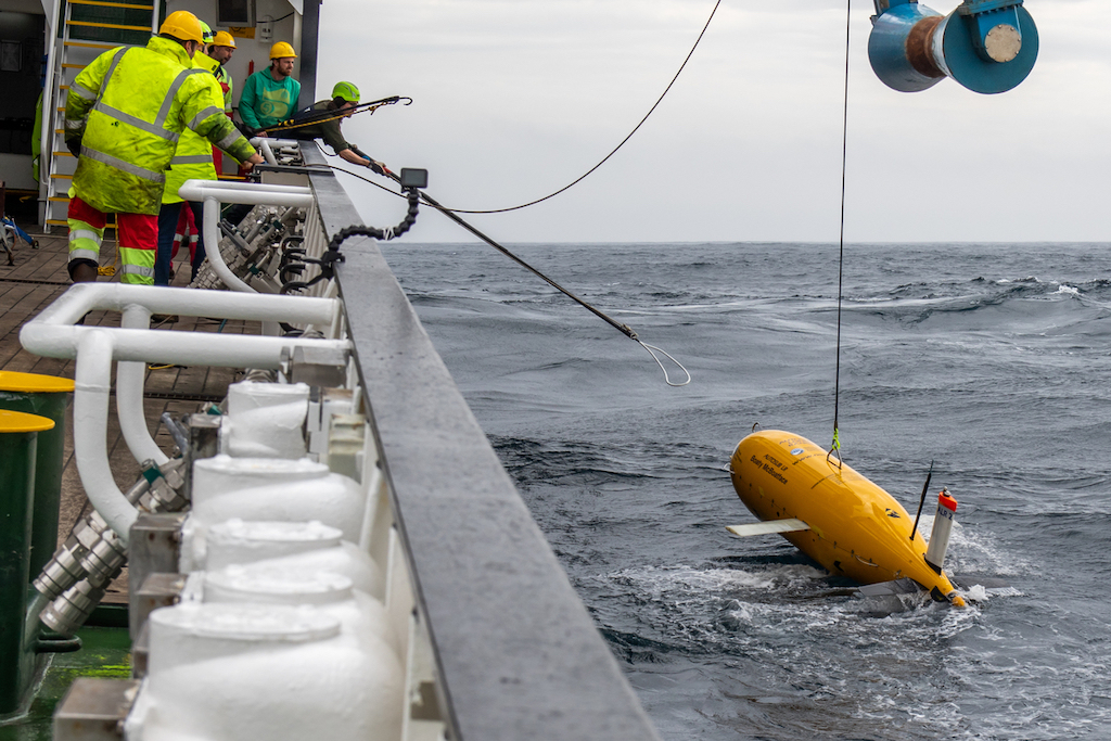 Crew members on a ship work to retrieve the autonomous underwater vehicle Boaty McBoatface from the water.