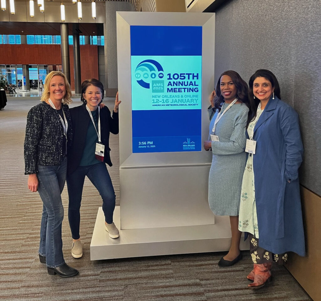 Kristen Averyt, Bernadette Woods Placky, Kandis Boyd, and Mona Behl standing by a sign welcoming attendees to the 2025 Annual Meeting in New Orleans.