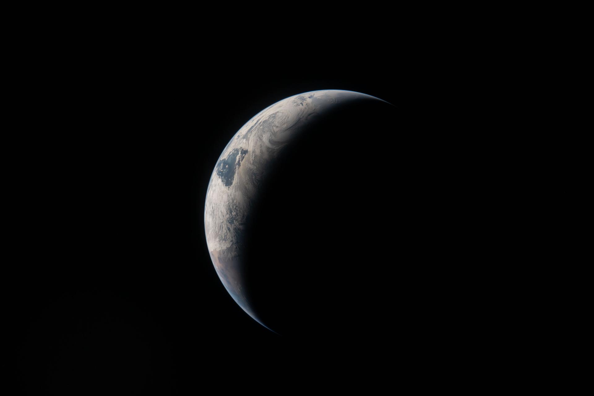 art002e009205 (April 4, 2026) - A thin arc glowing in the darkness of space. Sunlight traces the curves of the ocean and clouds, while the rest of the planet fades into shadow..
