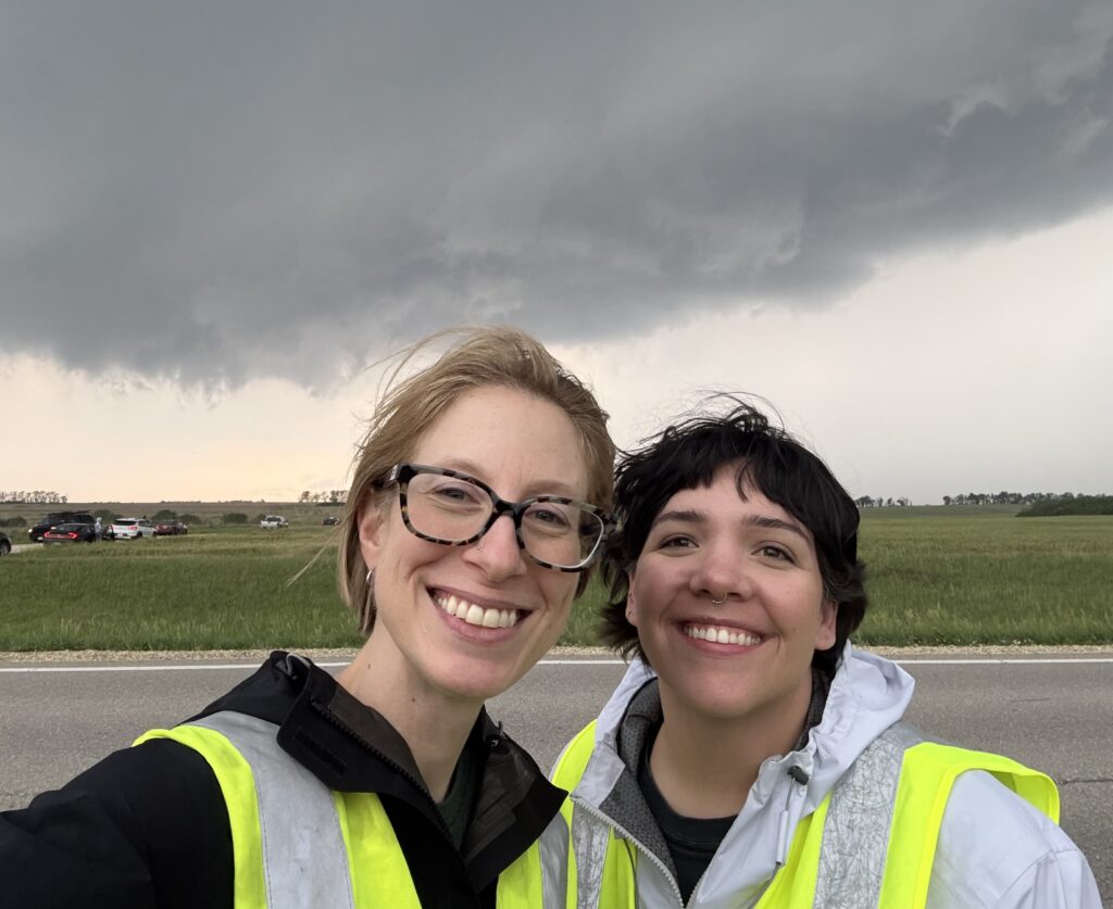 Photo of two women (Jen Walton and Anastasia Tomanek) in front of a storm cloud