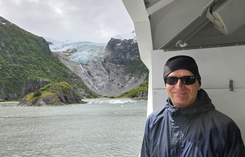 Tony Broccoli standing on a boat with a receding glacier in the background