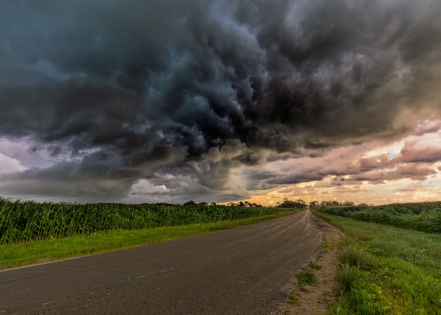 Dark clouds over a country road, with brighter skies in the distance