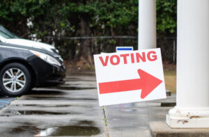 Photo of a voting sign outside a polling place on a rainy day. Source: Adobe Stock.