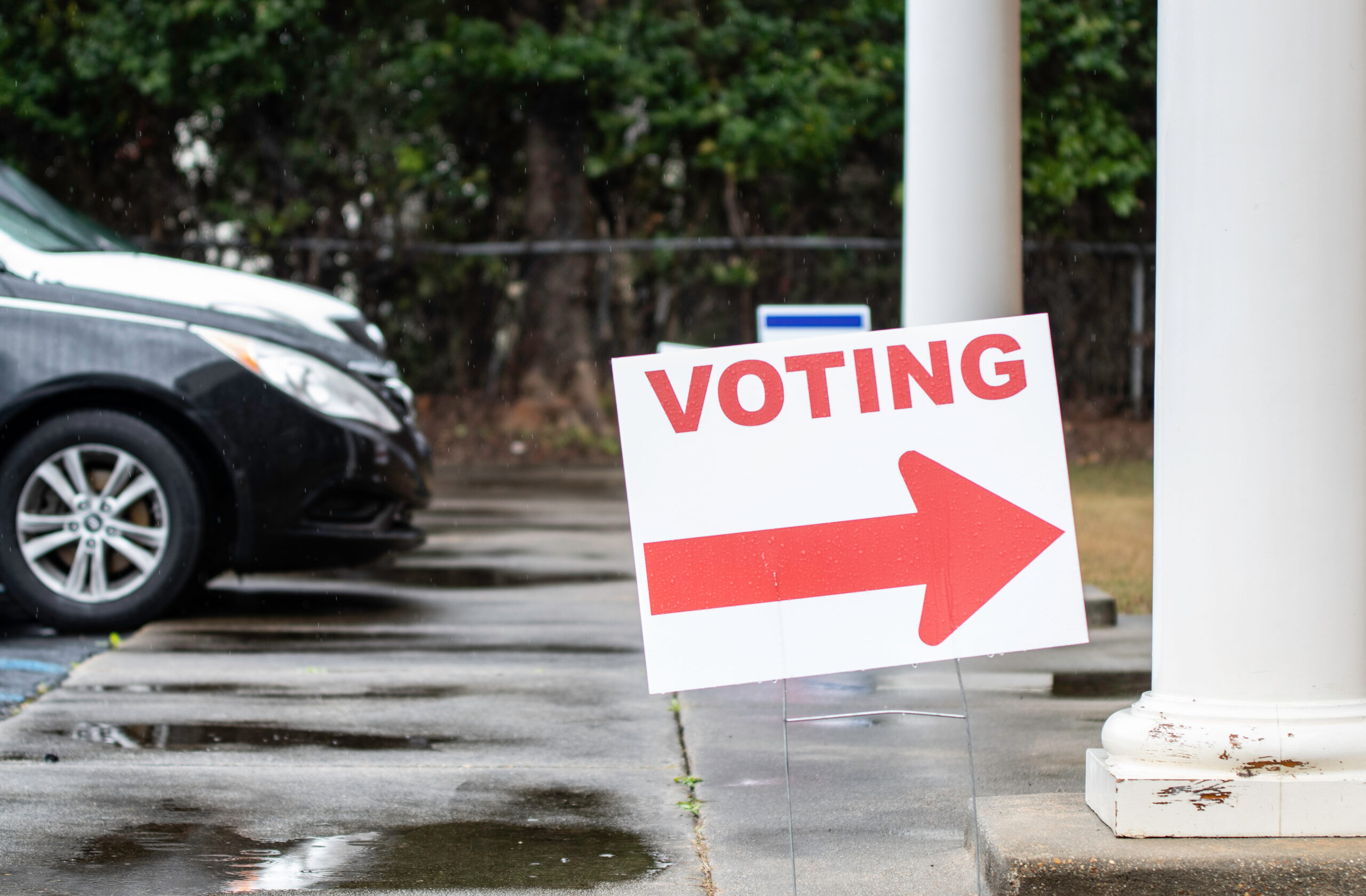 Photo of a voting sign outside a polling place on a rainy day. Source: Adobe Stock.